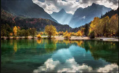 a lake with trees and mountains in the background at Cozy Nest in the heart of Kranjska Gora in Kranjska Gora