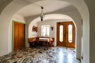 a dining room with a table and two doors at House, Garden and a Green Cat in Bled