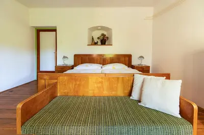 a bedroom with a large wooden bed with a bench at House, Garden and a Green Cat in Bled