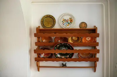a shelf with plates and bowls on a wall at House, Garden and a Green Cat in Bled