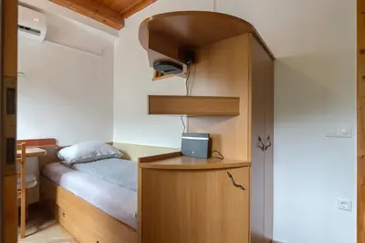 a small bedroom with a bed and a wooden cabinet at Cozy, Bright and Affordable Single Studio - Free Parking in Ljubljana