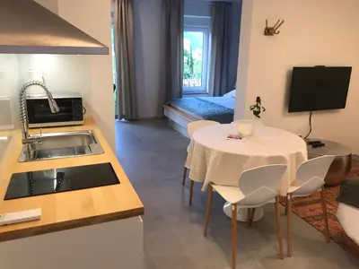a kitchen and living room with a table and a room with a bed at Vila Burbonka in Nova Gorica