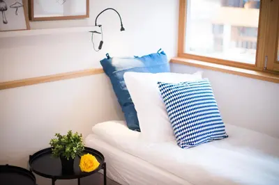 a white couch with a blue pillow and a window at Apartments Maison in Kranjska Gora