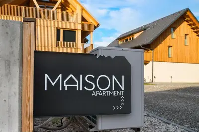 a sign in front of a building with a house at Apartments Maison in Kranjska Gora