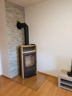 a wood stove in a room with a brick wall at Apartma Katja in Mojstrana