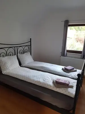 a bed with white sheets and pillows and a window at Apartma Katja in Mojstrana