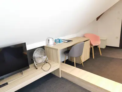 a room with a tv and a desk and chairs at Cha Cha Rooms in Ljubljana