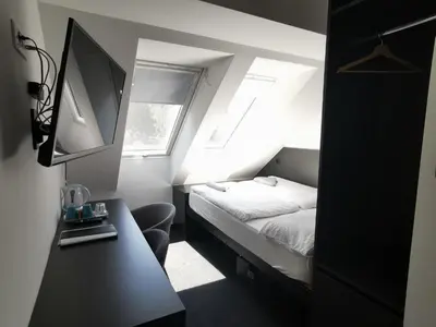 a small room with a bed and a desk with a computer at Cha Cha Rooms in Ljubljana