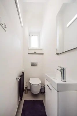 a white bathroom with a toilet and a sink at Kavon Apartments in Ljubljana