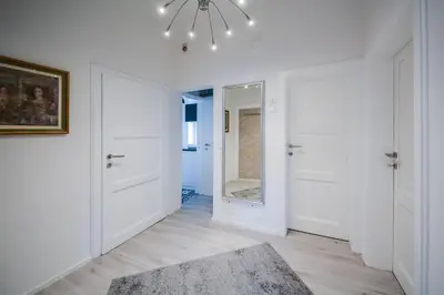 a hallway with white walls and a mirror and a rug at Kavon Apartments in Ljubljana