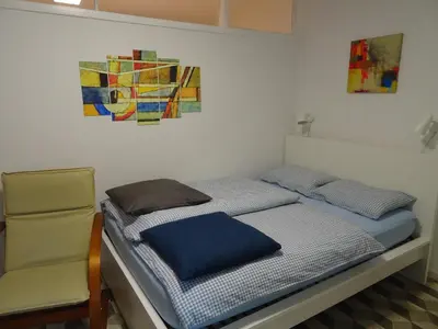 a bed with a chair and a painting on the wall at Apartma Nadja with private parking in Ljubljana