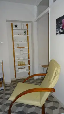 a living room with a yellow chair and a shelf at Apartma Nadja with private parking in Ljubljana