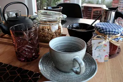 a table with a cup and plates and jars of food at Apartma Vita in Dobrovo