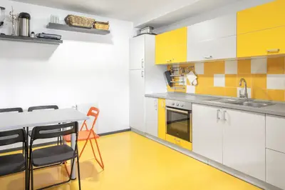 a kitchen with yellow and white cabinets and a table and chairs at Youth Hostel Trbovlje in Trbovlje