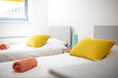 a bedroom with two beds with yellow and orange pillows at Youth Hostel Trbovlje in Trbovlje