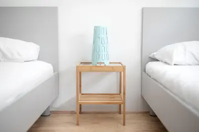 a bedside table with a mirror next to two beds at Youth Hostel Trbovlje in Trbovlje