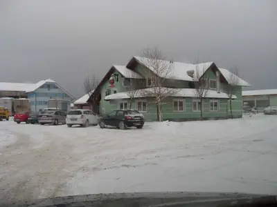 a green house with cars parked in a parking lot at Rooms En Krajcar in Cerknica