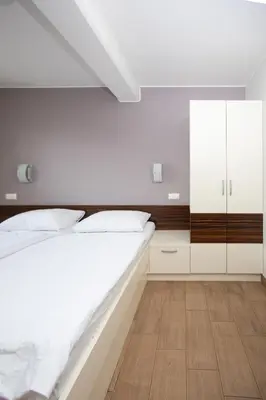 a white bedroom with a large bed and white cabinets at Rooms En Krajcar in Cerknica