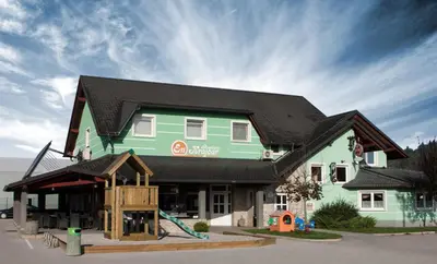 a large green building with a black roof at Rooms En Krajcar in Cerknica