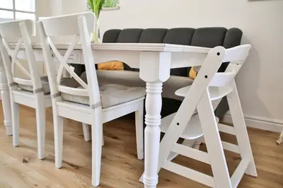 a table with four white chairs around it at Historic Mexico Building Apartment in Ljubljana