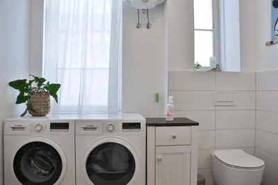 a white laundry room with a washer and dryer at Historic Mexico Building Apartment in Ljubljana