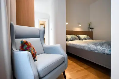 a bedroom with a blue chair and a bed at City Centre Chic Apartment Ljubljana 2/4 in Ljubljana