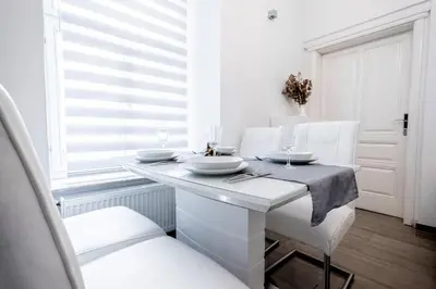 a white dining room with a white table and chairs at Kenti Residence in Ljubljana