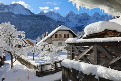 a house covered in snow with mountains in the background at Apartma Felix in Kranjska Gora