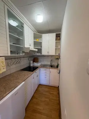 a kitchen with white cabinets and a wooden floor at Apartma Snežko in Kranjska Gora