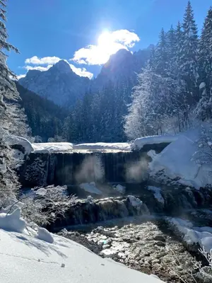 a waterfall in the snow with mountains in the background at APARTMA KATKA Vila Mojca in Kranjska Gora
