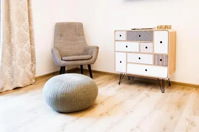 a chair and a ottoman in a room with a dresser at Hiša 109 in Kranjska Gora