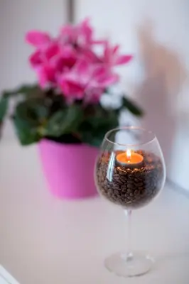 a candle in a wine glass next to a flower pot at Apartments Special Bled in Bled