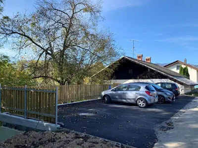two cars parked in a parking lot next to a fence at Old Boatman's House in Bled