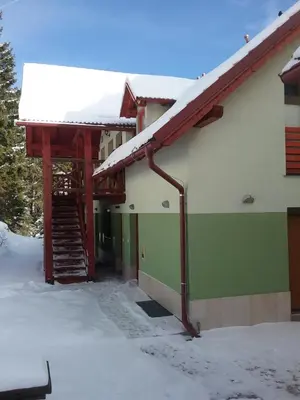 a building with snow on the roof and a staircase at Hudinja 111 in Vitanje