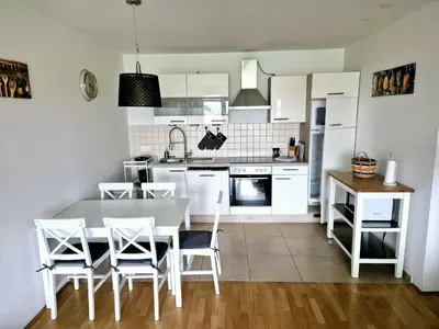 a kitchen with white cabinets and a table and chairs at Apartmaji PANONIA 