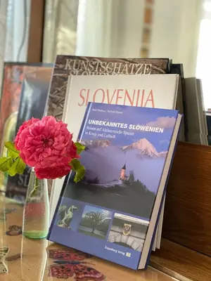 two books on a table next to a vase with a flower at Guesthouse Sabine - pr` Skminc in Bohinjska Bela