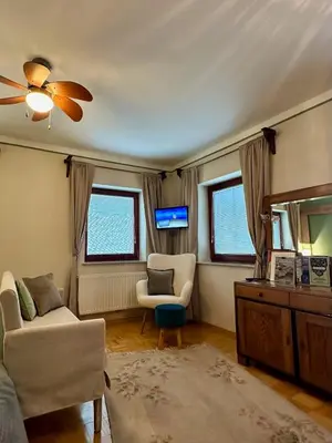 a living room with a couch and a chair and a television at Guesthouse Sabine - pr` Skminc in Bohinjska Bela