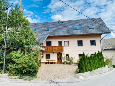 a large white house with a wooden porch at Guesthouse Sabine - pr` Skminc in Bohinjska Bela