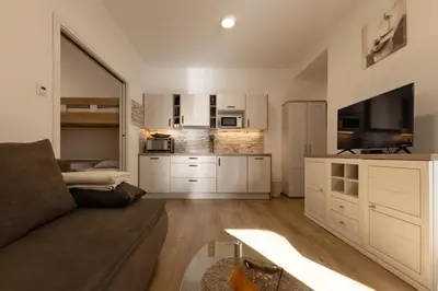 a living room with a couch and a tv and a kitchen at Apartmaji 