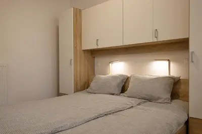 a bedroom with a large bed with white cabinets at Apartmaji 