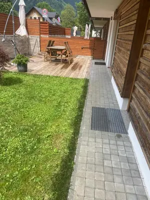 a patio with a table and a grass yard at Apartma Pika in Mojstrana