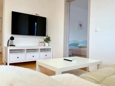 a white living room with a tv on a wall at Guest house Kobal in Spodnje Gorje