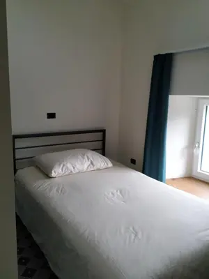 a bedroom with a white bed with a blue curtain at B & W KRIŽ in Ajdovščina