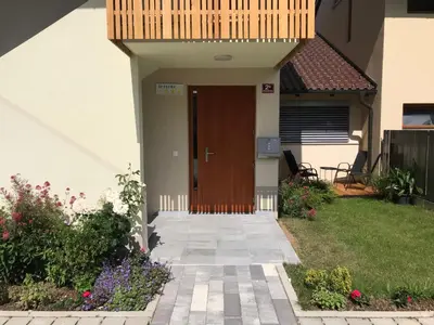 a house with a brown door and some flowers at Klinar - Cosy apartment with a terrace in Bled