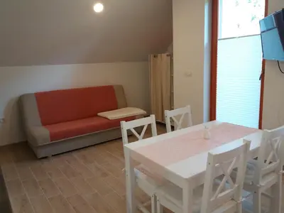 a living room with a couch and a table and chairs at APARTMA BREMEC-STUDIO in Bohinj