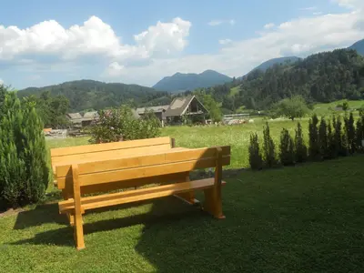 a wooden bench sitting in the grass in a field at APARTMA BREMEC-STUDIO in Bohinj