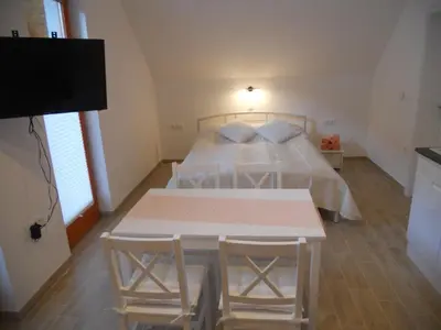 a bedroom with a bed and a table with chairs at APARTMA BREMEC-STUDIO in Bohinj