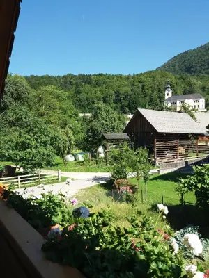 a view of a garden with a barn and flowers at APARTMA BREMEC-STUDIO in Bohinj