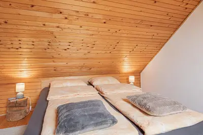 two beds in a room with a wooden ceiling at Holiday house Podhamer Boris in Presika