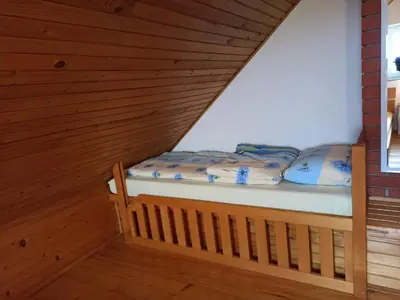 a small bed in a room with wooden walls at Holiday house Podhamer Boris in Presika